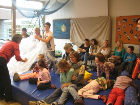 Das Foto zeigt Schülerinnen und Schüler, Eltern und Kollegen beim szenischen Spiel einer Geschichte.