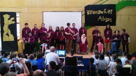 Das Foto zeigt die Entlass-Schülerinnen und Entlass-Schüler im einheitlichen Motto-T-Shirt auf der Bühne der LVR-Schule am Königsforst.