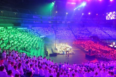 Die vollen Tribünen der Lanxess-Arena sind in verschiedenen Farben angestrahlt und alle stehen und singen.