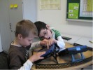 Das Foto zeigt zwei Schüler im Umgang mit einem Sprachcomputer.