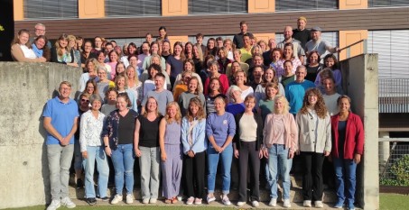 Gruppenfoto aller Mitarbeiter und Mitarbeiterinnen der Schule draußen auf der Treppe des Neubauhofes