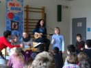 Das Foto zeigt Fug und Janina, die gemeinsam mit Schülerinnen und Schülern bei ihrem Mitmachkonzert Musik machen.