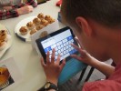 Das Foto zeigt einen Schüler im English Café , der auf einem Tablet-PC eine Bestellung tippt.