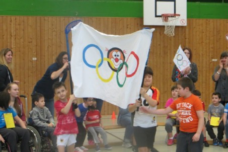 Das Foto zeigt Schülerinnen und Schüler, die die olympische Fahne schwenken.