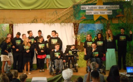Die Schülerinnen und Schüler stehen mit ihren schwarz-grünen Motto-Sweatshirts auf der Bühne mit Dschungelcamp-Logo.