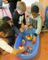 Auf dem Bild sieht man Schülerinnen und Schüler um eine mit Wasser gefüllte Wanne herum sitzen. In der Wanne schwimmen aus Lego gebaute Schiffe.