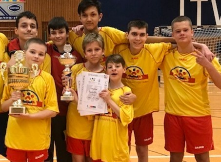 Die Mannschaft in gelben Trikots auf einem Gruppenbild mit Siegerpokal.