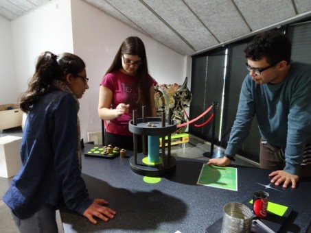 Zwei Schülerinnen und ein Schüler experimentieren mit einer Apparatur zur Überprüfung der Stabilität von Körpern.