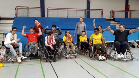 Ein Gruppenfoto der Rösrather Rollstuhlbasketballer mit Lehrer. Sie jubeln und strahlen.