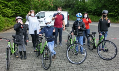 Schüler*innen, Schulleitung und Mitarbeiter der Verkehrswacht mit den neuen Fahrrädern auf dem Schulparkplatz.