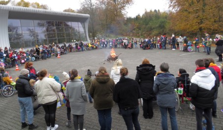 Foto: Schüler und Schülerinnen mit Laternen vor der Schule, in der Mitte brennt ein Feuer