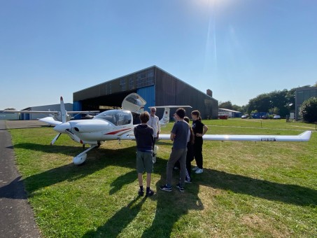 Foto: Herr Martiny und ein paar Schüler*innen stehen vor einem Flugzeug.
