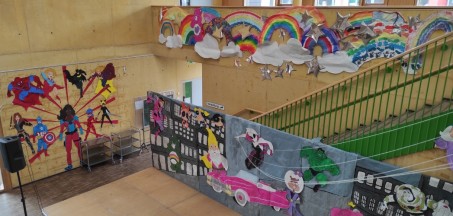 Foto: Selbst gestaltete Kulisse hinter der Bühne und an der Wand der Eingangshallen mit vielen bunten Motiven von Superhelden und anderen Fantasiefiguren.