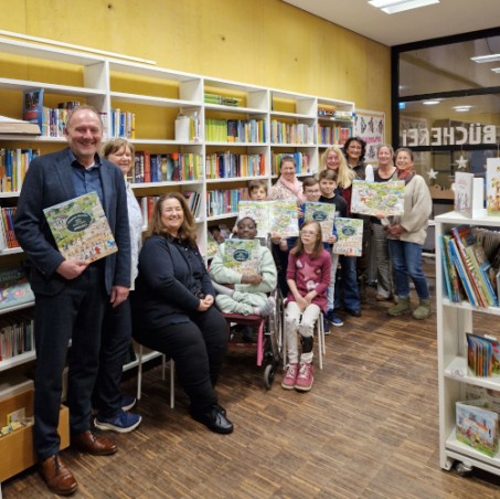 Gruppenbild von der Übergabe des Wimmelbuchs in der Schulbücherei.