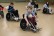 Foto: In extra Rugbyrollstühlen wird von Schüler*innen Rollstuhl-Rugby gespielt. Dabei wird ein Ball auf dem Schoß transportiert und hinter die Linie der Gegner gebracht.