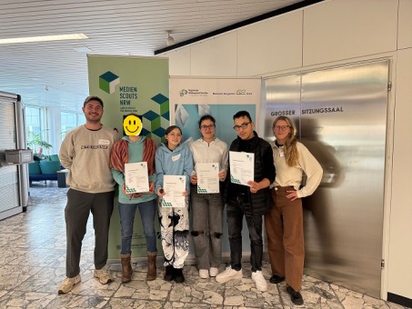 Foto: Die Medienscouts der LVR Schule am Königsforst erhalten eine Urkunde vor dem Kreishaus vom Rheinisch-Bergischen-Kreis vor einem Banner.