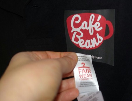 Das Logo des Schulcafés Café Beans auf dem Polo-Shirt mit dem "Fair Wear"-Siegel.