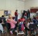 Foto: Auf Leinwand vor einer Schüler*innengruppe präsentiert eine Frau Bilder.