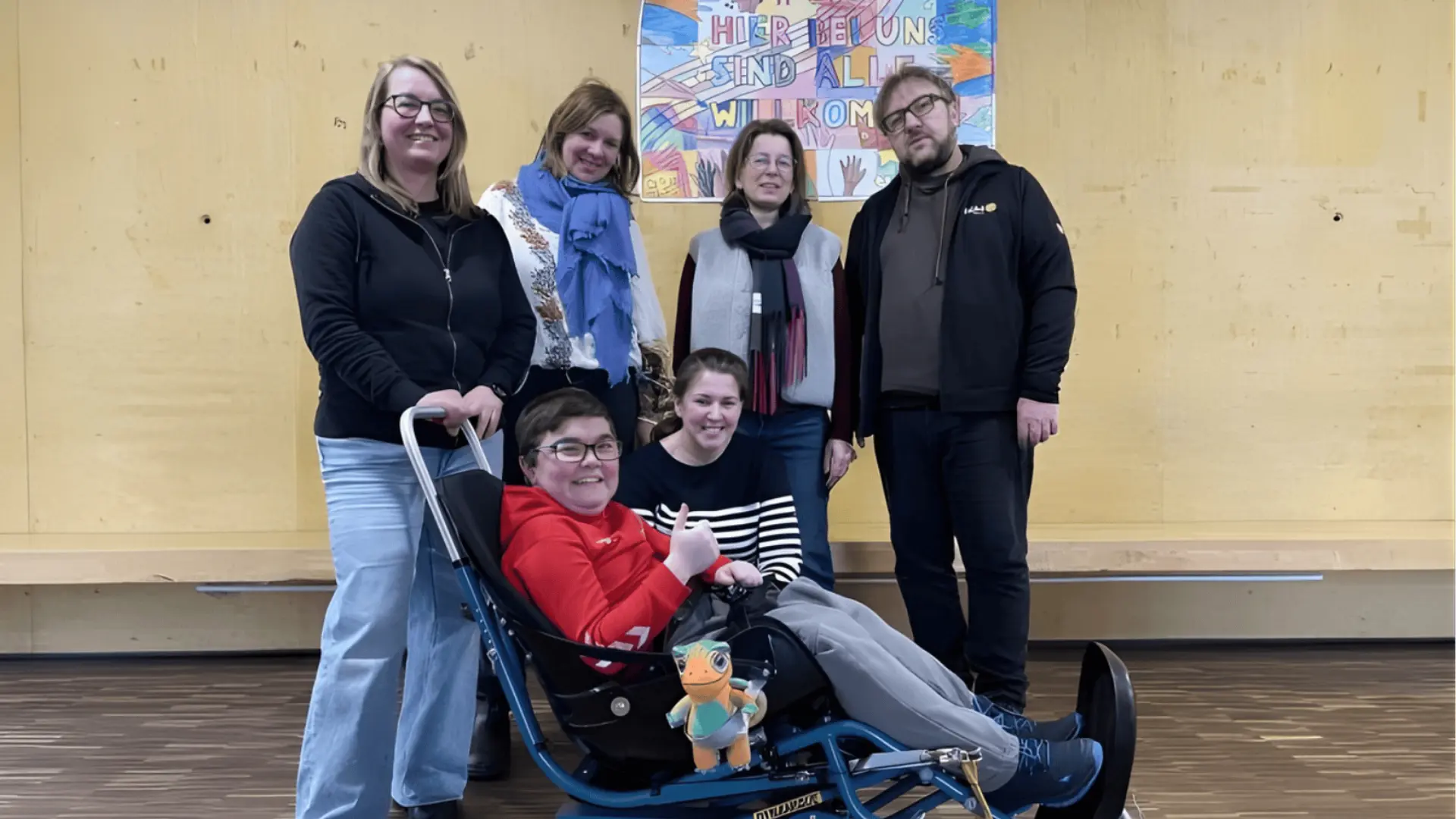 Der neue Skibob mit seinem ersten Skifahrer und dem Maskottchen von KiNiKi, den Spender*innen, der Schulleitung und Lehrerinnen vom Skiteam der Schule